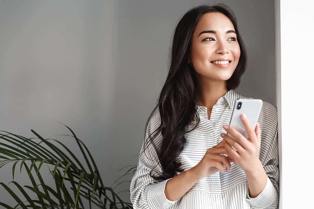 Woman Smiling While Looking at Her Phone